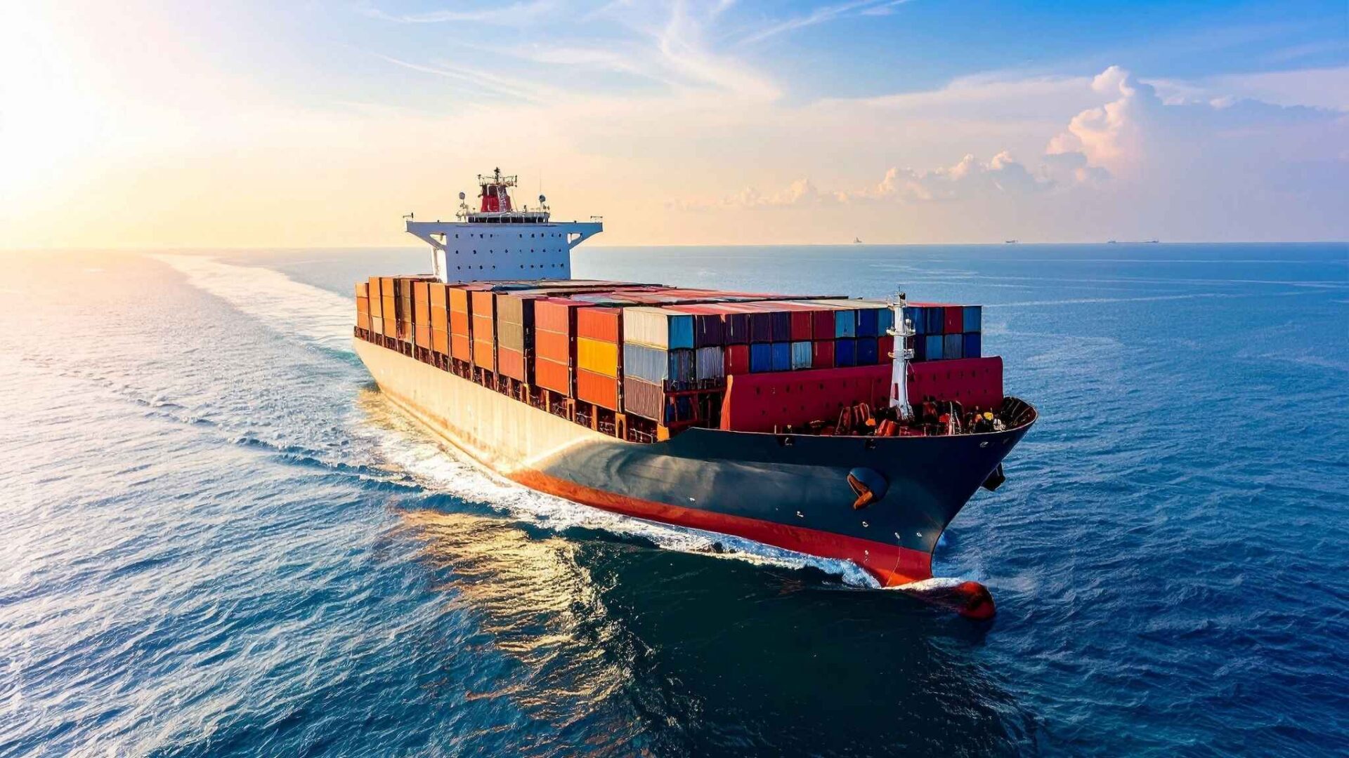 Barco de carga navegando en el océano con contenedores de colores durante el atardecer