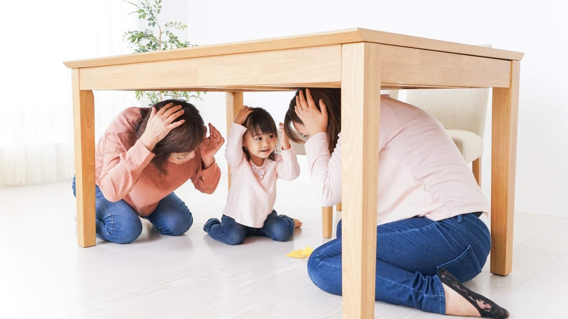 familia protegiéndose debajo de una mesa durante un terremoto siguiendo medidas de seguridad en casa