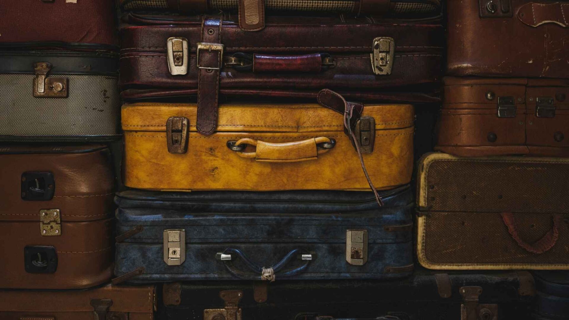 Maletas antiguas apiladas de diferentes colores, representación de sueños con maleta y su significado